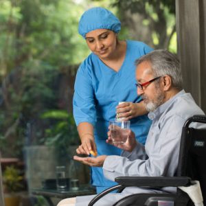Female nurse giving medicine to disabled old man on wheelchair